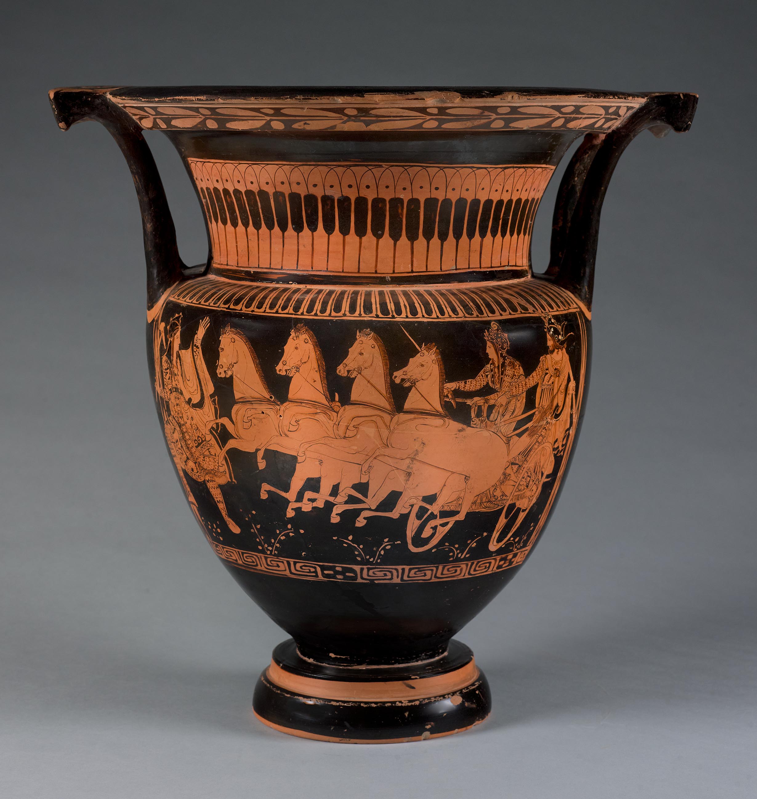 One view of a vase, the body depicting a chariot pulled by four horses, with a charioteer and passenger, as well as a third figure in front of the chariot